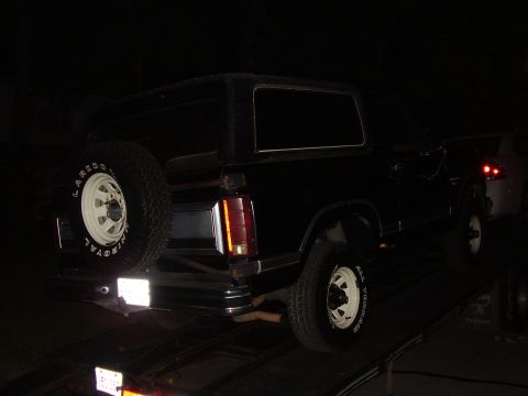 1986 Ford Bronco - Rear view of a black 1986 Ford Bronco, showing its spare tire mounted on the tailgate.