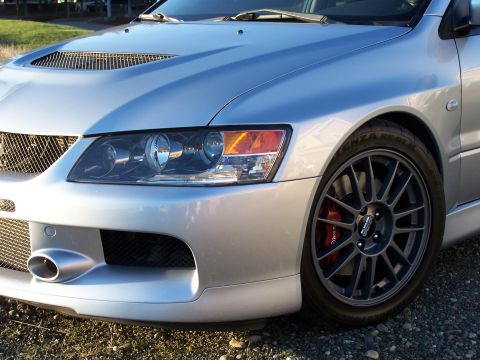 1995 Ford Probe - Close-up of a silver Mitsubishi Lancer Evolution VIII's front end, showing its distinctive hood scoop and alloy wheel.