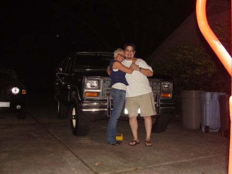 1986 Ford Bronco - A couple poses in front of a dark-colored Ford Bronco at night.