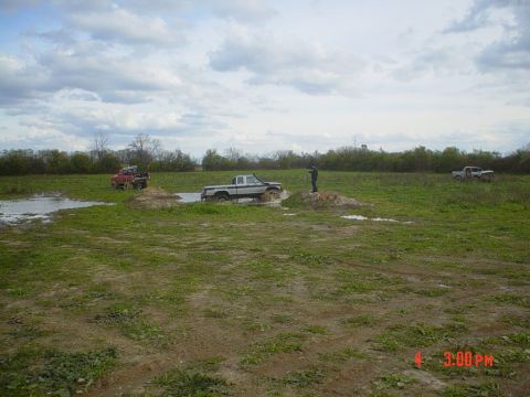 1990 Ford Ranger - Several trucks are navigating a muddy off-road course under a cloudy sky.