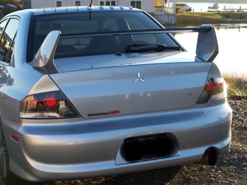 1995 Ford Probe - The rear of a silver Mitsubishi Lancer Evolution MR is shown parked outdoors near a body of water.