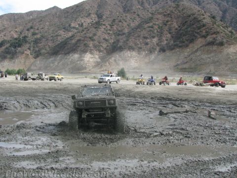 1987 Suzuki Samurai - A Suzuki Samurai navigates a muddy off-road course with other vehicles in the distance.
