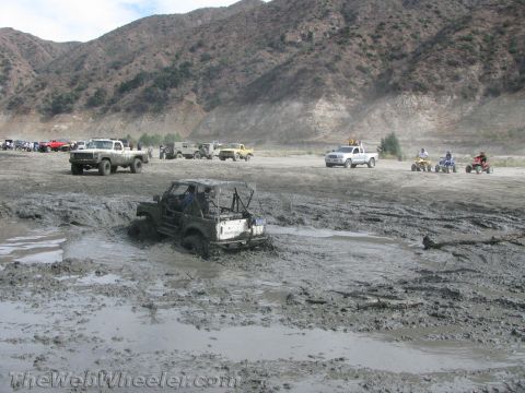1987 Suzuki Samurai - Multiple off-road vehicles are stuck in a muddy terrain, with a white Suzuki Samurai prominently featured.