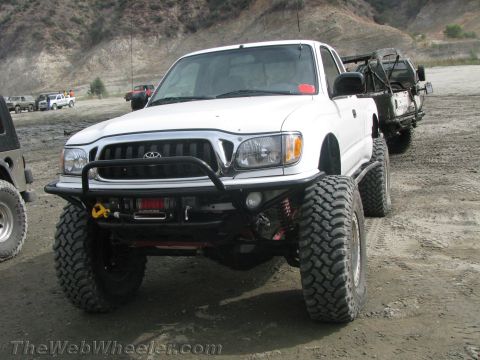 1987 Suzuki Samurai - A modified white Toyota Tacoma pickup truck is seen off-road, with another vehicle visible behind it.