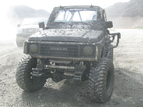 1987 Suzuki Samurai - A heavily mud-caked 1987 Suzuki Samurai is shown from the front, with another vehicle in the background.