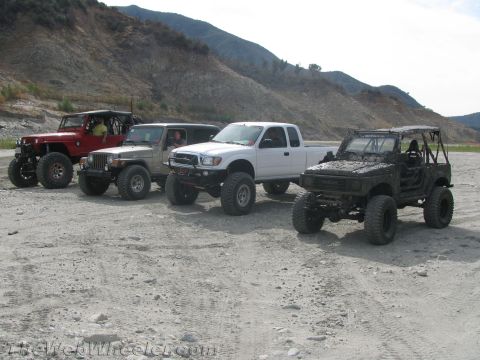 1987 Suzuki Samurai - Four off-road vehicles are parked in a line on a dirt lot with hills in the background.