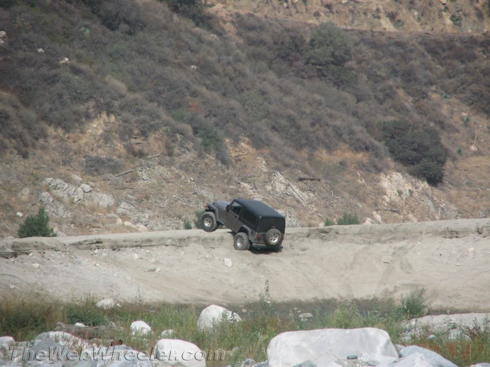 Black off-road vehicle on a dirt path with a rocky hillside