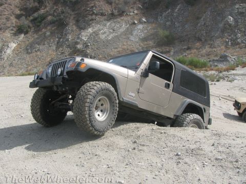 1987 Suzuki Samurai - A tan Jeep Wrangler navigates sandy terrain, with another vehicle visible in the background.