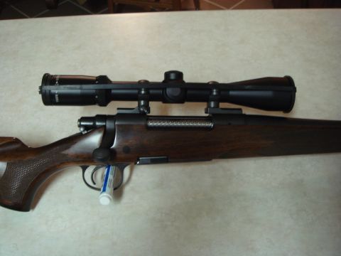 1992 Ford Bronco - A rifle with a scope is shown on a table. A tube of lubricant is placed in the trigger guard.