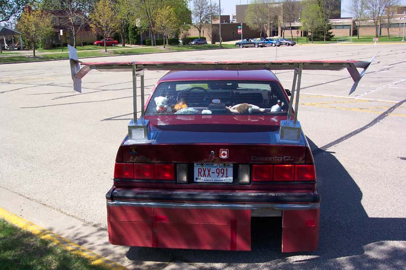 Red sedan rear view with large spoiler and license plate RXX-991