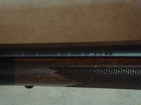 1992 Ford Bronco - Close-up of a bolt-action rifle barrel stamped "REMINGTON ARMS COMPANY INC. ILION, NY 270 WIN" above a checkered walnut forend with a black…