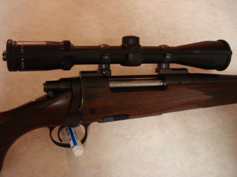 1992 Ford Bronco - A rifle with a scope is shown, a wooden stock and metallic components.