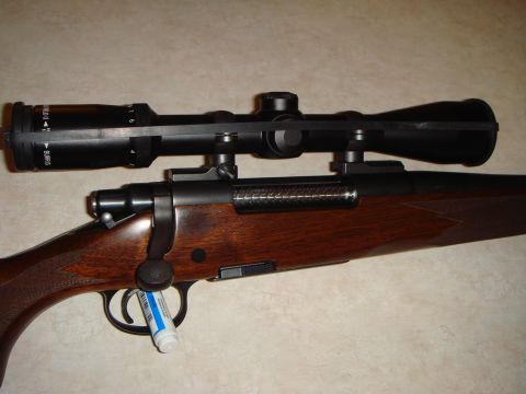 1992 Ford Bronco - Close-up view of a rifle with a scope mounted on top and a wooden stock.