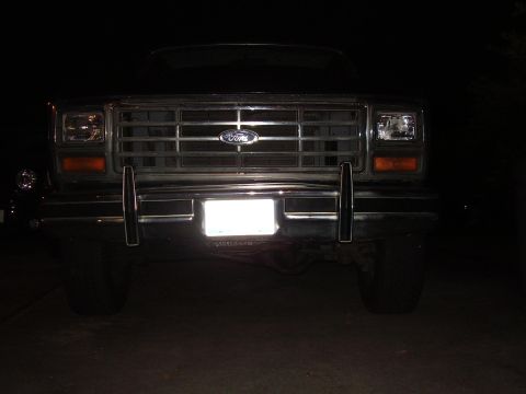 1986 Ford Bronco - The front grille and bumper of a Ford truck are visible in the dark.
