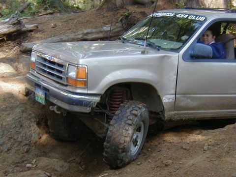 2005 Jeep Wrangler - Ford Explorer tackles rough terrain on a wooded trail, showing off its off-road capabilities.