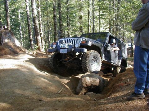 2005 Jeep Wrangler - A black 2005 Jeep Wrangler navigates a challenging off-road trail with a person watching.
