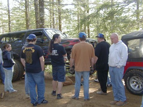 2005 Jeep Wrangler - A group of people gather around a lifted black Ford Bronco with flame decals during an outdoor event.