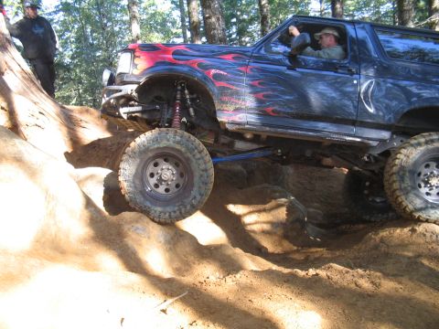 1989 Ford Bronco - This modified Ford Bronco navigates a challenging off-road trail with steep inclines and rocky terrain.