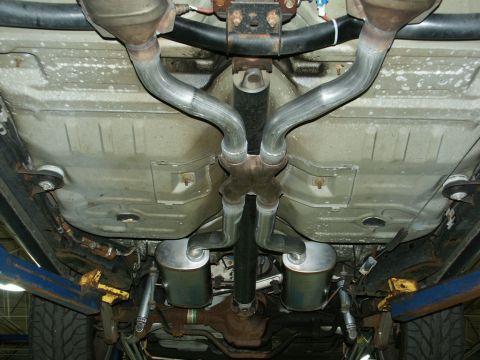 2001 Mercury Grand Marquis - The underside of a vehicle displays a custom dual exhaust system with two mufflers and a crossover pipe.