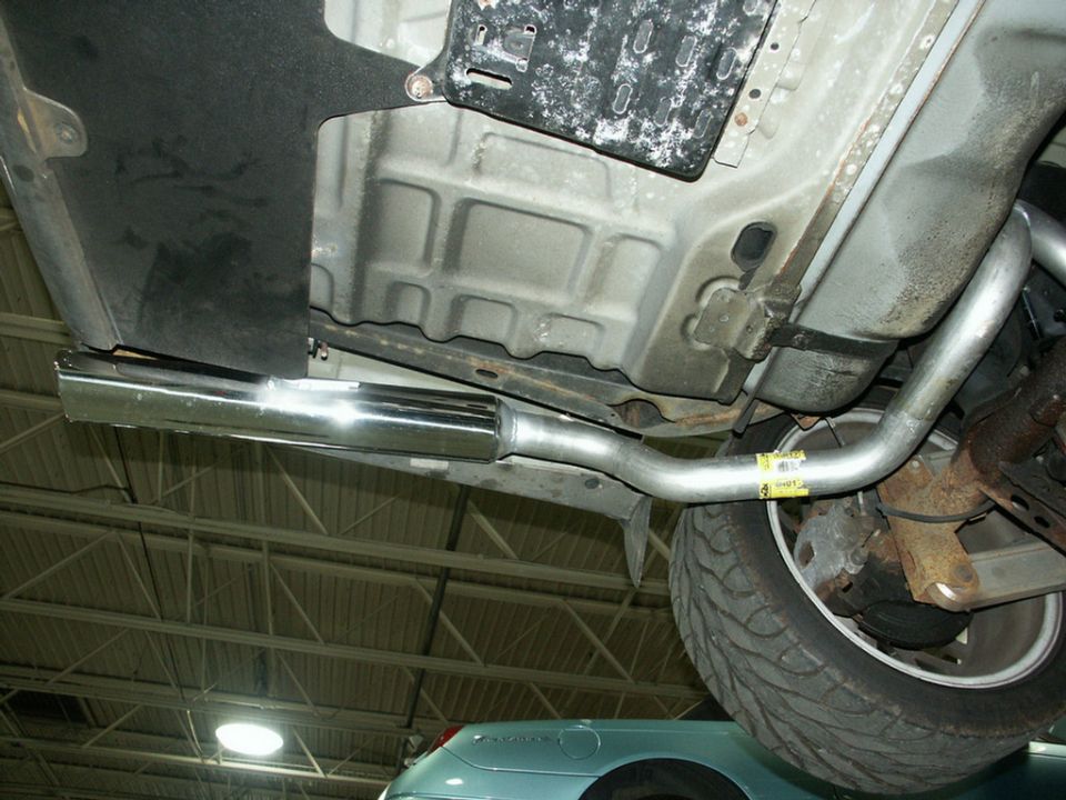 Underbody of a car on a lift with new polished stainless exhaust and muffler