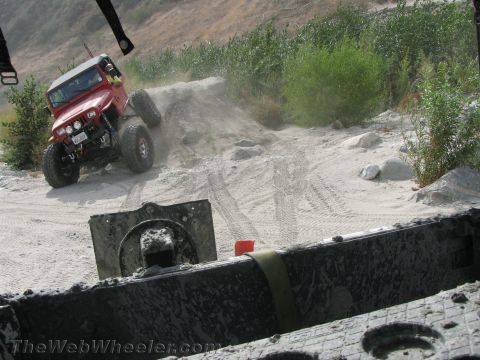 1987 Suzuki Samurai - A red Jeep Wrangler navigates a dusty off-road trail, with the year 1987 visible on its license plate.