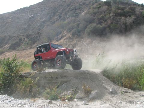 1987 Suzuki Samurai - Off-road Jeep navigating a dusty trail on a hillside.