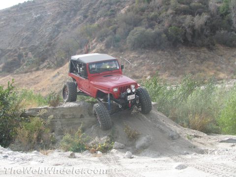 1987 Suzuki Samurai - A modified Jeep Wrangler navigates a steep, sandy incline in a dry, hilly landscape.