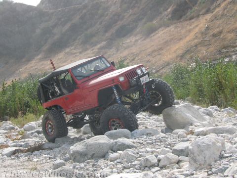 1987 Suzuki Samurai - Modified Jeep Wrangler navigating a rocky obstacle course in a natural environment.