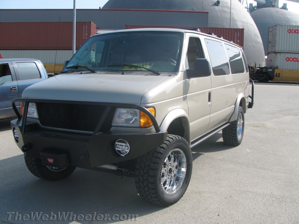 Tan lifted Ford Econoline van with steel front bumper, brush guard and off-road tires