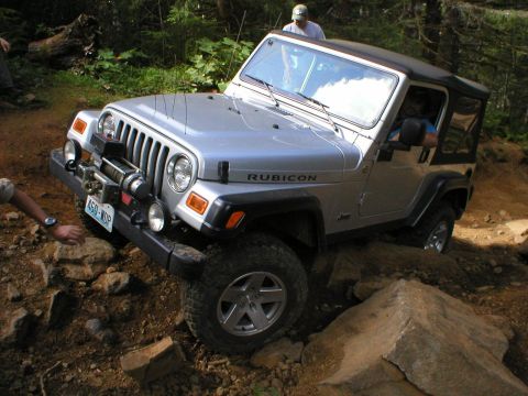 2005 Jeep Wrangler - A Jeep Wrangler Rubicon navigates a rocky off-road trail with a person visible in the driver's seat.