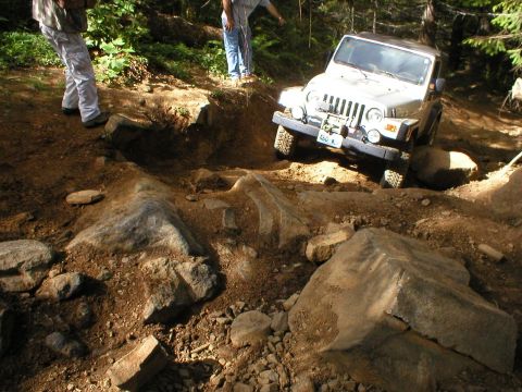 2005 Jeep Wrangler - Silver 2005 Jeep Wrangler tackling a challenging rocky path with two observers present.