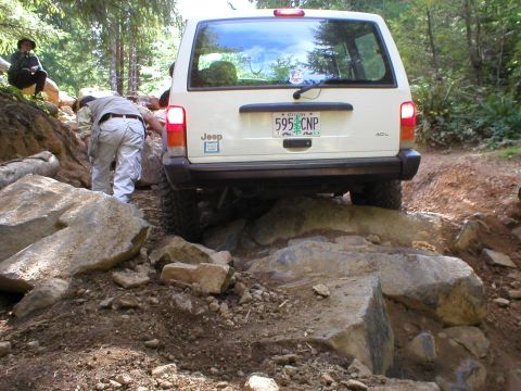 2005 Jeep Wrangler - A white Jeep Cherokee XJ navigates a challenging rocky off-road path.