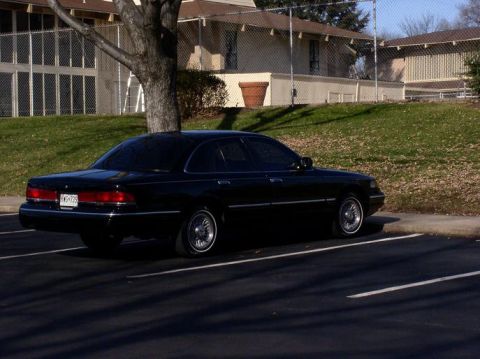 1997 Ford Crown Victoria - Side view of a black 1997 Ford Crown Victoria sedan in a parking lot.