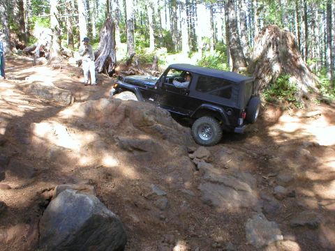 2005 Jeep Wrangler - Jeep Wrangler TJ tackling a challenging rocky trail in a wooded area.