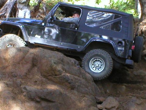 2005 Jeep Wrangler - A black Jeep Wrangler navigates a rocky off-road course, with its tires gripping the terrain.