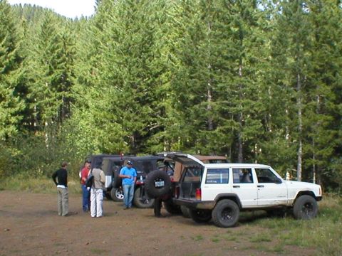 2005 Jeep Wrangler - Several Jeeps are gathered in a wooded area with people standing around them.