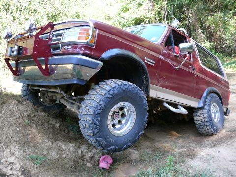 1988 Ford Bronco - This modified Ford Bronco is shown from a three-quarter front angle, equipped with large off-road tires and a custom front bumper.