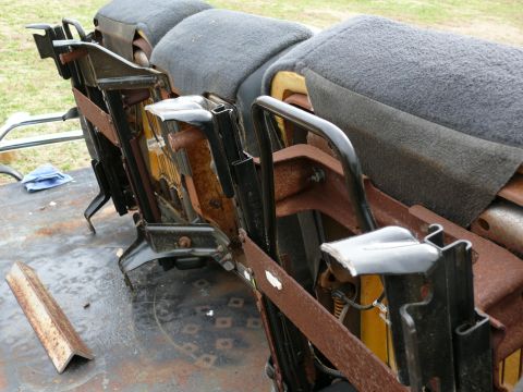 1988 Ford Bronco - Close-up view of heavily rusted seat frames, likely from an older vehicle, showing the internal metal structure and grey fabric upholstery.