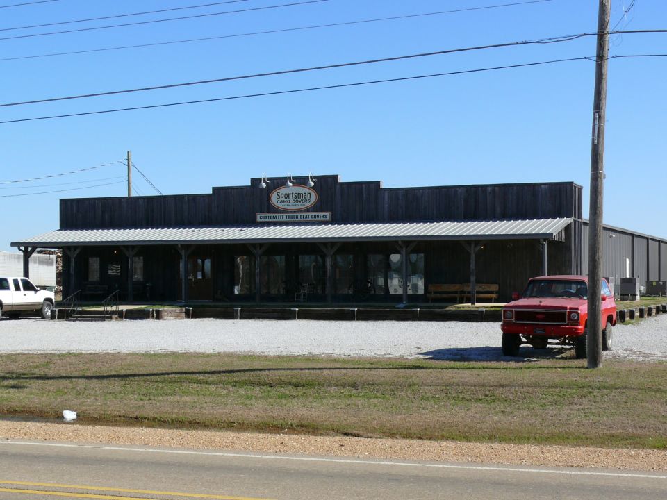 Red SUV parked in front of a building with a white truck to the left