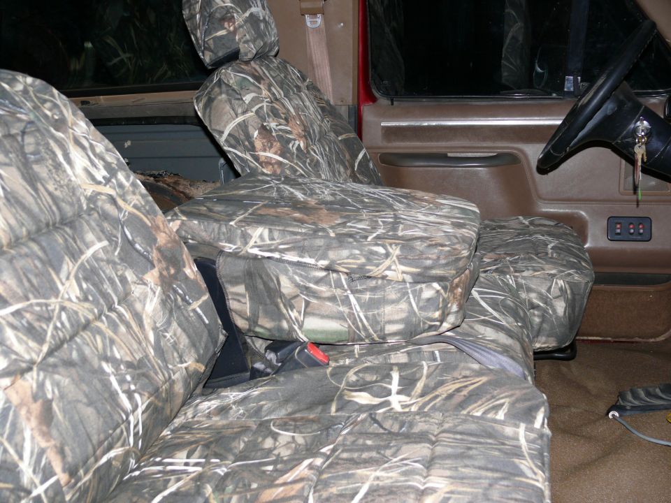 Camouflage seat covers in a vehicle interior, showing front seats and dashboard details