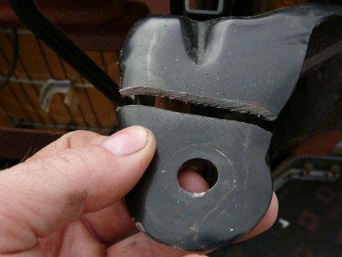 1988 Ford Bronco - A close-up shows a fractured metal bracket, likely from a vehicle seat, with visible damage to its structure.