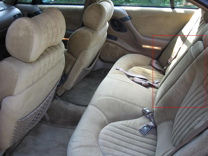 Back seat and door panel of a car interior. Has a red box highlighting the rear door handle and light