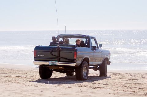 1979 Ford Bronco - Rear view of a 1979 Ford Bronco on the beach, with passengers enjoying the ocean view.