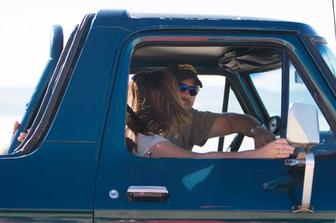 1979 Ford Bronco - Two people inside a dark blue SUV, with the driver looking towards the passenger.