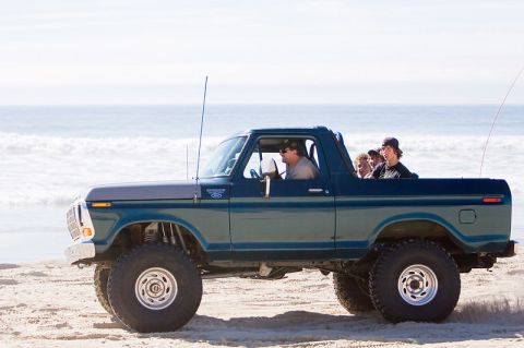 1979 Ford Bronco - A 1979 Ford Bronco drives along the sandy shore with passengers enjoying the ocean view.