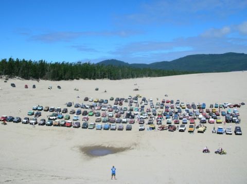 1979 Ford Bronco - A large group of vehicles gathered on sand dunes under a blue sky.