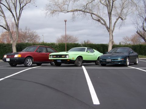 1996 Ford Probe - Three cars are parked in a lot under a cloudy sky.