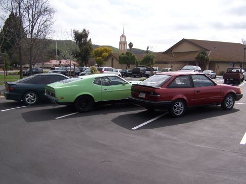 1996 Ford Probe - Multiple vehicles are parked in a lot with buildings and trees in the background.