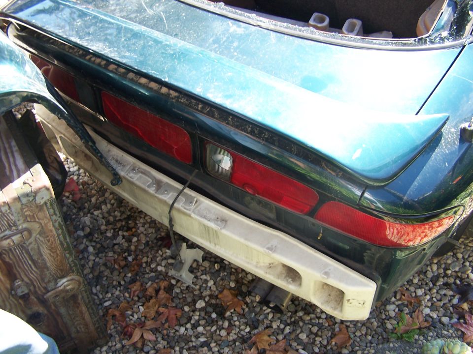 Teal car's rear bumper and taillights, damaged