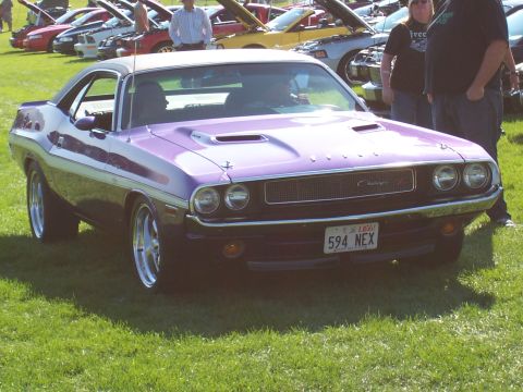1973 Ford Mustang - A purple 1970 Dodge Challenger is displayed at a car show with other vehicles present.